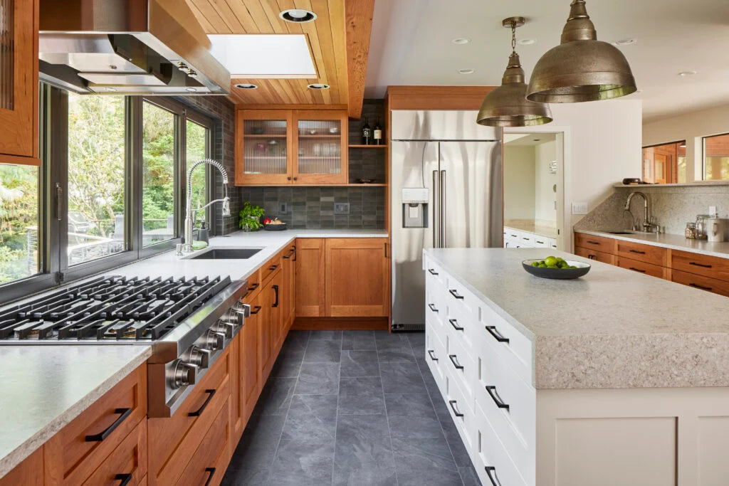 Updated kitchen featuring wood cabinetry, white quartz island with storage drawers, stainless steel range and refrigerator, oversized windows, and modern pendant lights in Sun Prairie, WI.